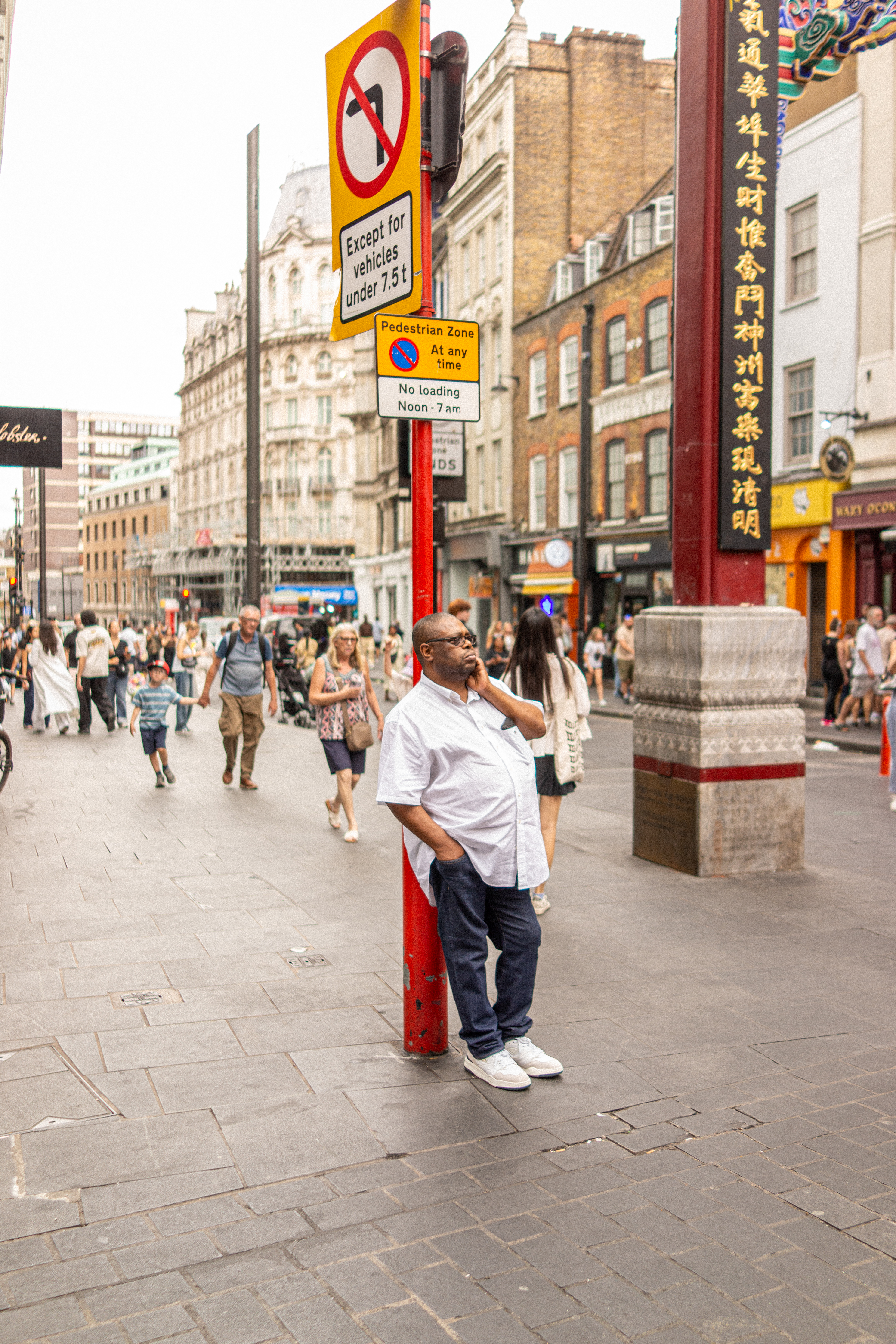 A man waiting leaning on a pole